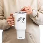 A person wearing a beige hoodie holds a white insulated travel tumbler with a handle and clear lid. The tumbler has a black mountain graphic and the text 'BEYOND THE MILES' with smaller motivational text, and the brand name 'koozie' near the bottom.