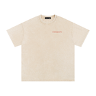 A light beige short-sleeve t-shirt with a subtle mineral wash texture, featuring the word 'MONACO'S' printed in red on the left chest. The brand 'SAVORI' is visible on the inner neck label.