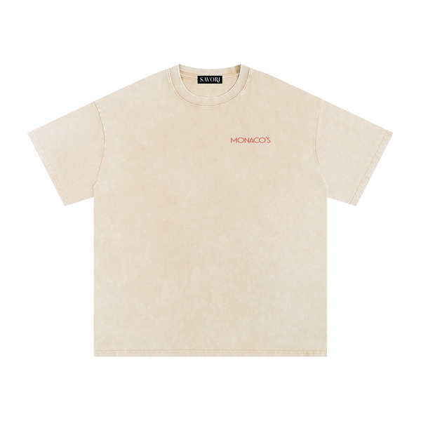 A light beige short-sleeve t-shirt with a subtle mineral wash texture, featuring the word 'MONACO'S' printed in red on the left chest. The brand 'SAVORI' is visible on the inner neck label.