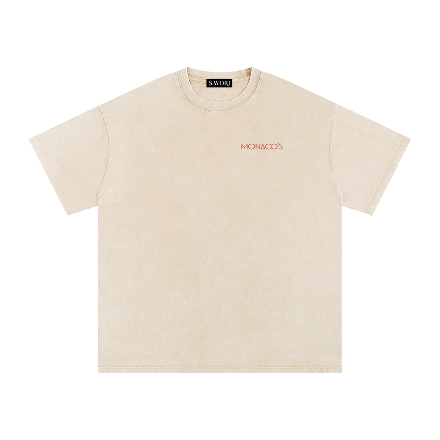 A light beige short-sleeve t-shirt with a subtle mineral wash texture, featuring the word 'MONACO'S' printed in red on the left chest. The brand 'SAVORI' is visible on the inner neck label.
